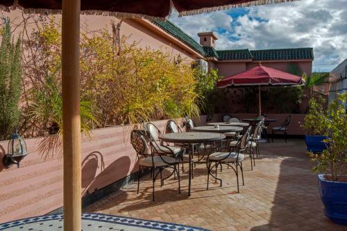 an outdoor patio with tables and chairs and umbrellas at Riad Merzouga in Marrakech