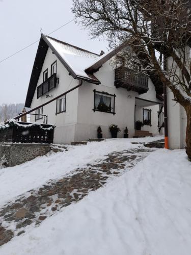 a white house with snow in front of it at Casa Victoria in Moieciu de Sus