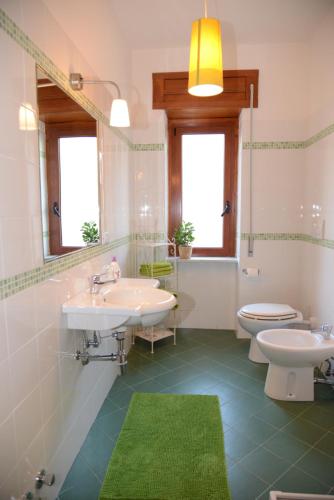 a bathroom with two sinks and a toilet and a mirror at Jonico Guest House in Scanzano