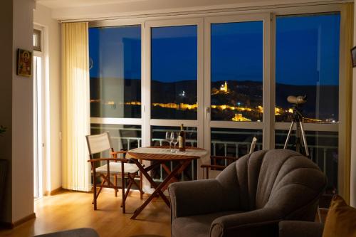 a living room with a table and a large window at Tsarevets panoramic apartments Veliko Tarnovo in Veliko Tŭrnovo