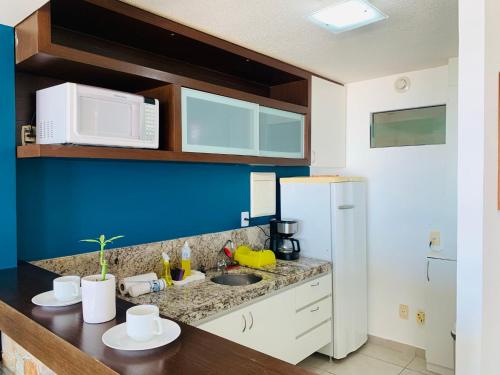 a kitchen with a counter with a microwave and a sink at Maravilhoso flat com vista para o Mar de Ponta Negra in Natal