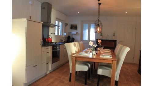 a kitchen with a wooden table with chairs and a refrigerator at Chalet Buutengeweun, met luxe JACUZZI en TONSAUNA in Sint Annaland