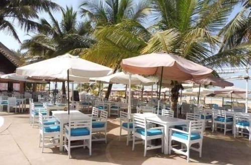 un montón de mesas y sillas con sombrillas en la playa en safari village case 29, en Saly Portudal