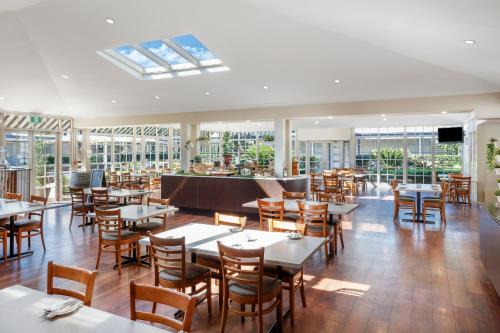 un restaurante con mesas, sillas y ventanas en Crowne Plaza Hawkesbury Valley, an IHG Hotel, en Windsor