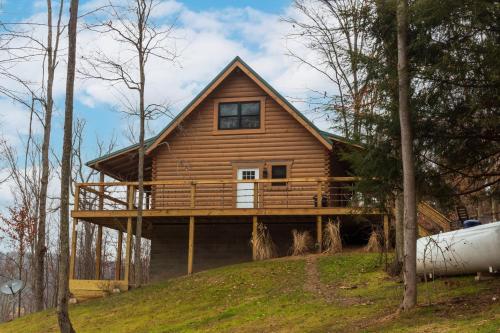 a log house with a deck on a hill at Pine Creek HC Hocking Hills Cabins in South Bloomingville