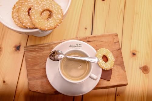 a cup of coffee and donuts on a wooden table at Hotel Zimmerbräu in St. Wolfgang