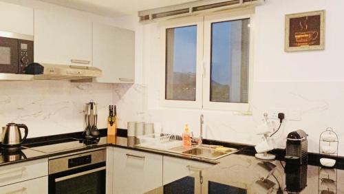 a white kitchen with a sink and some windows at Studio Jebel Sifah Resort Golf Lake G 14 - 201 in As Sīfah