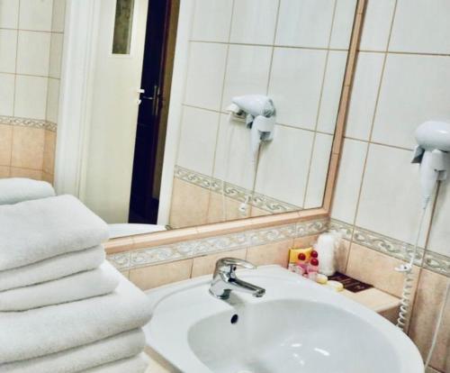 a bathroom with a sink and a mirror and towels at Matejko Hotel in Kraków