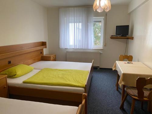 a bedroom with two beds and a table and a window at Grüne Au Hotel in Hasselroth