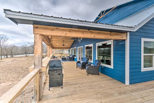 a blue house with a deck with chairs and a grill at Upscale Riverfront Home with Beach and Fire Pit! in Glenwood