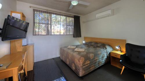 Dormitorio con cama, escritorio y TV en Gunnedah Motor Inn, en Gunnedah