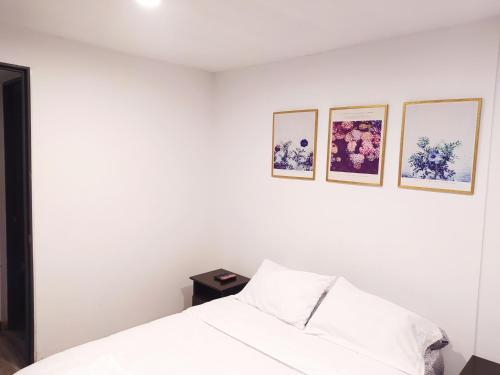 1 dormitorio blanco con 1 cama y 3 cuadros en la pared en 7 Apartamento dos habitaciones Cedritos Minimalista, en Bogotá