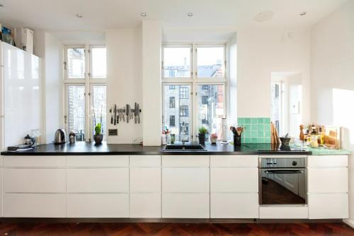una cocina con armarios blancos y encimeras negras en ApartmentInCopenhagen Apartment 1357, en Copenhague
