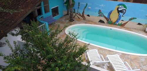 ein Pool mit Stühlen und ein Vogelbild in der Unterkunft Atlântico in Maresias