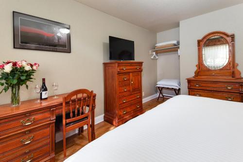 a bedroom with a bed and a dresser with a tv at Stratford Inn in Ashland