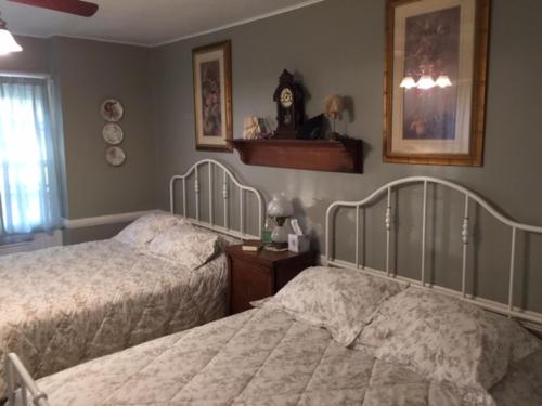 a bedroom with two beds and a clock on the wall at Willard Richards Inn in Nauvoo