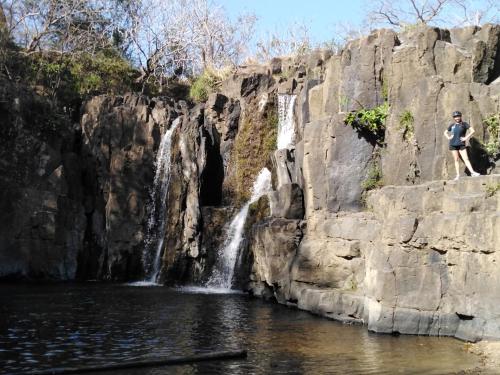 a man standing on a cliff next to a waterfall at The Blue House Panama in Chame