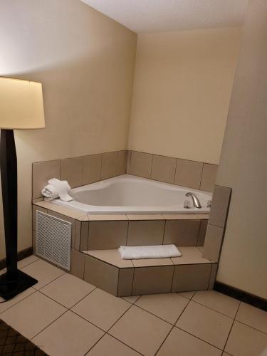 a bath tub in a room with a lamp and towels at Home Inn & Suites in Montgomery