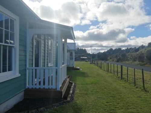 a blue house with a fence next to a road at Taylor Lodge in Erua