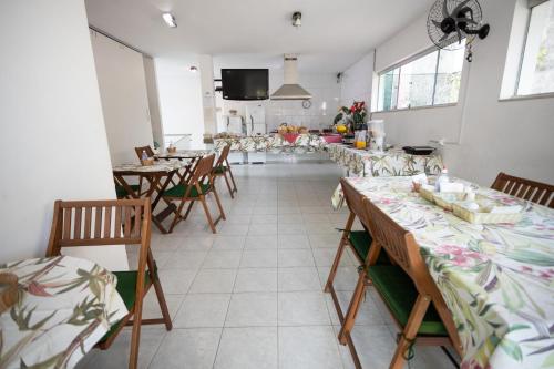 a dining room with tables and chairs and windows at Pousada Palmeira Real in Itaguaí