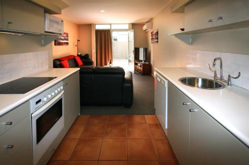 a kitchen with a sink and a couch in a room at Queenstown Gateway Apartments in Queenstown