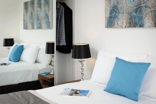 a bedroom with two beds with blue pillows and a mirror at Park Avenue - IKON Glen Waverley in Glen Waverley