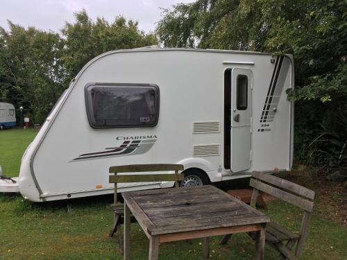 a white caravan parked next to a wooden table at Thomas's Catlins Lodge and Camp Ground in Owaka