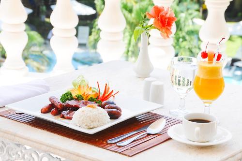 a plate of food on a table with a drink at Paradise Garden Hotel and Convention Center Boracay Powered by ASTON in Boracay