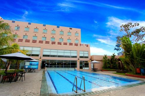 a hotel with a swimming pool in front of a building at Forbis Hotel in Serang