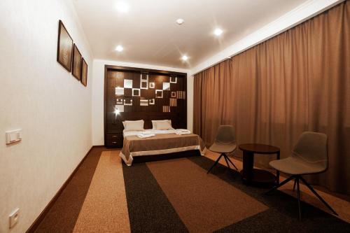 a bedroom with a bed and a table and chairs at Meridian in Karagandy