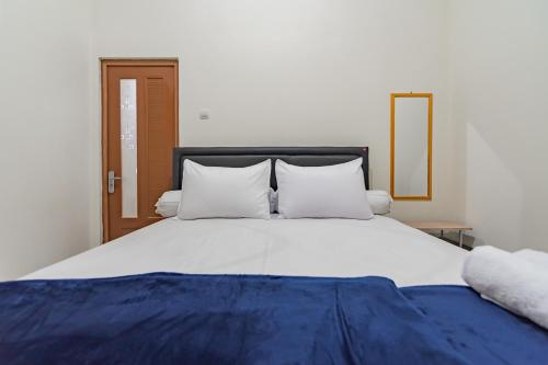 a large white bed with two pillows on it at The Lima Guest House Syariah Mitra RedDoorz in Cirebon