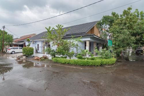 a house in a flooded street with a car at The Lima Guest House Syariah Mitra RedDoorz in Cirebon