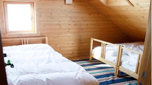 a bedroom with two beds in a wooden cabin at Pension Kamifuji in Osaki