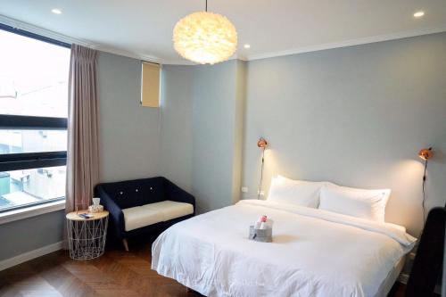 a bedroom with a bed and a chair and a window at Hygge Kro in Hualien City