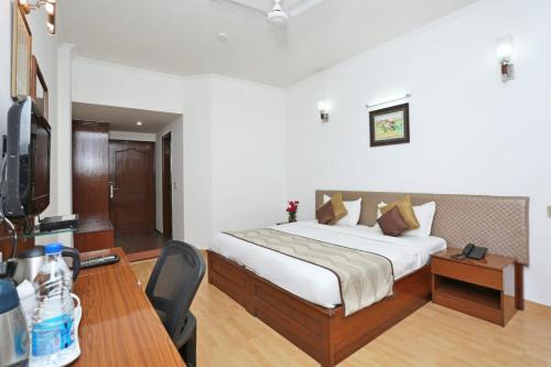a bedroom with a bed and a desk and a television at Hotel Exotica Leisure Valley in Gurgaon