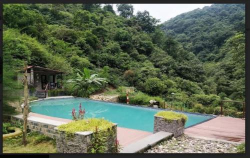 una piscina en medio de una montaña en Haut Monde Hill Stream Resort and Spa, en Dehradun