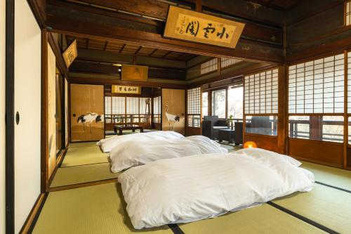 a room with three beds with white sheets at Temple Hotel 正暦寺 in Ayabe