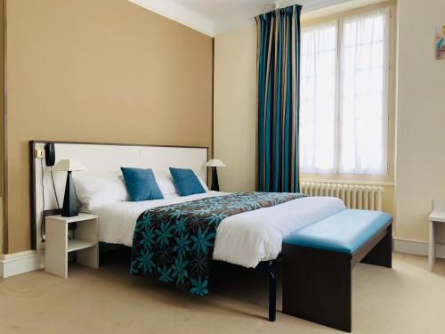 a bedroom with a large bed with blue pillows at Au Petit Vivoin in Vivoin
