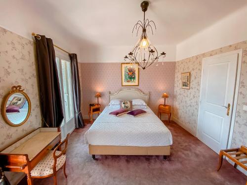 a bedroom with a bed and a mirror and a chandelier at Hotel Relais Du Postillon in Antibes