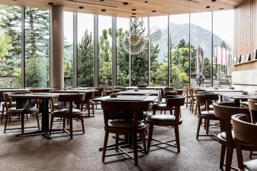 a restaurant with tables and chairs and large windows at Eden Hotel in Bormio