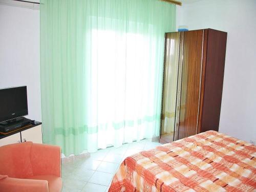 ein Schlafzimmer mit einem Bett, einem Stuhl und einem Fenster in der Unterkunft Apartments Lovran in Lovran