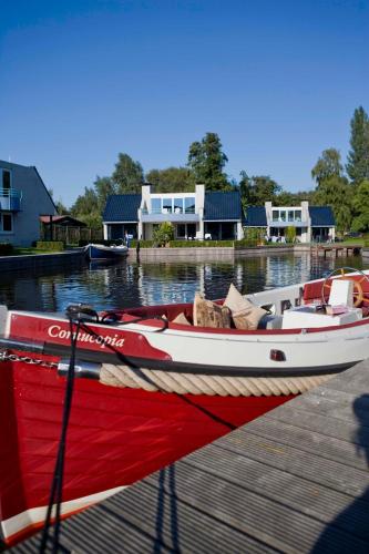 a red and white boat is docked at a dock at Amsterdam / Loosdrecht Rien van den Broeke Village in Loosdrecht