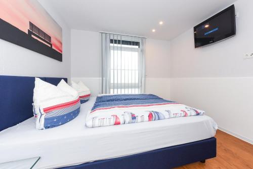 a bedroom with a bed with a tv on the wall at Ferienwohnungen MARENOR in Bensersiel
