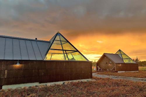 two barns and a barn with a sunset in the background at Elves Village Hotel in Levi