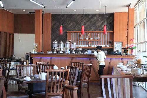 a woman standing at the bar of a restaurant at Aerotel Smile Losari in Makassar