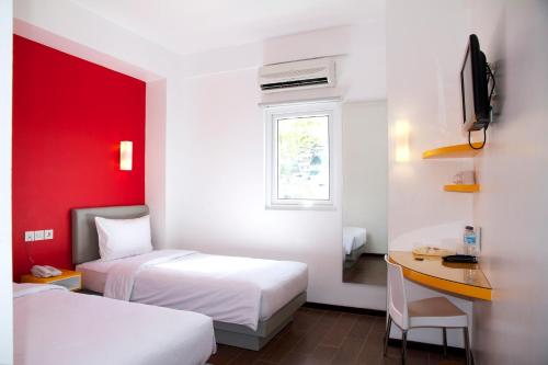 a hotel room with two beds and a desk and a window at Amaris Hotel Ambon in Ambon