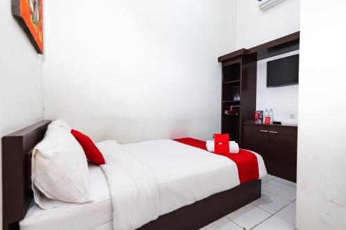 a bedroom with a white bed and a television at RedDoorz @ Hertasning Area 2 in Makassar