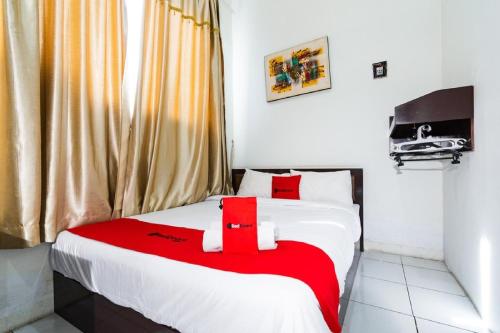 a bedroom with a bed with a red blanket at RedDoorz @ Hertasning Area 2 in Makassar