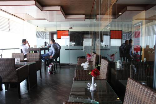 a group of people sitting at a table in a restaurant at Aerotel Smile Losari in Makassar