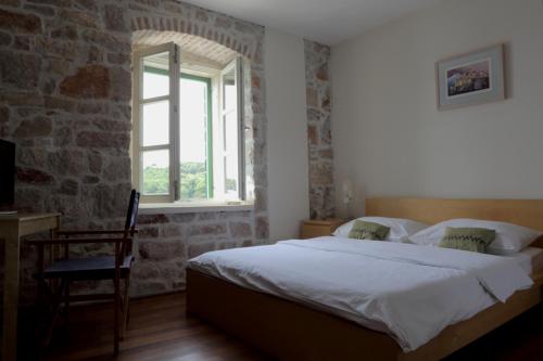 a bedroom with a bed and a window and a chair at Hotel Maestral in Prvić Luka